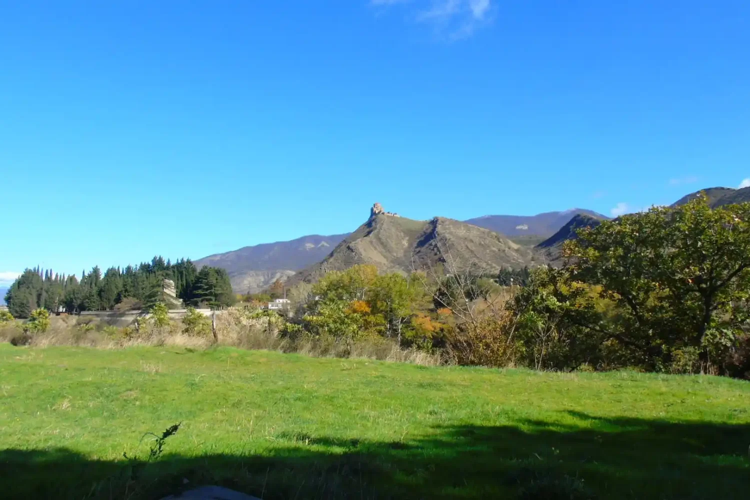 Distant view of Jvari Monastery on a green mountain peak