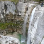 Travelers looking at Kinchkha waterfall cascading into a natural pool