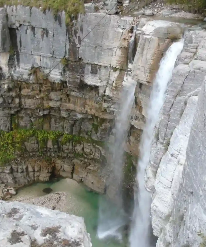 Travelers looking at Kinchkha waterfall cascading into a natural pool